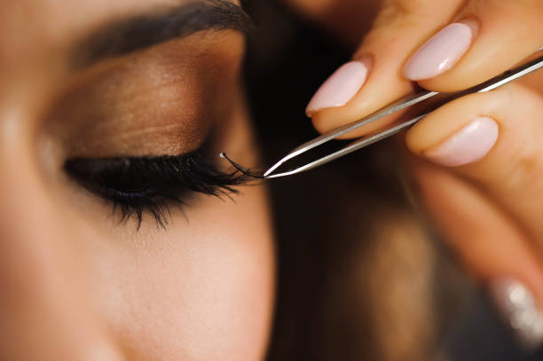 Close up of professional stylist lengthening lashes for female client in a beauty salon. stock photo