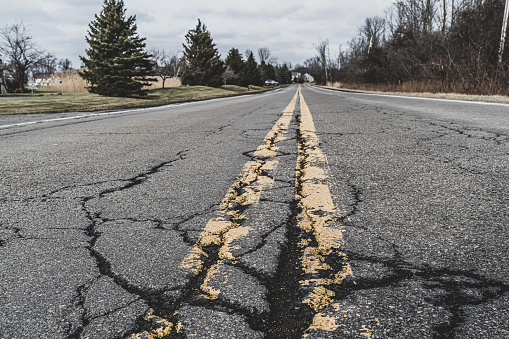 Close up of road markings and cracked asphalt of a suburban road.  Grand Island, New York.