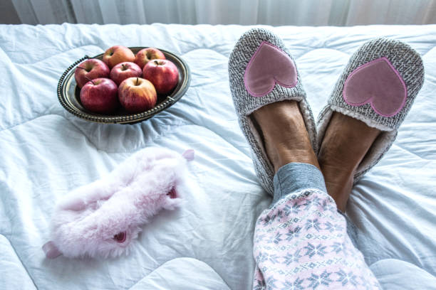 Close Up of Senior Woman Legs in Fluffy Slippers on the Bed stock photo