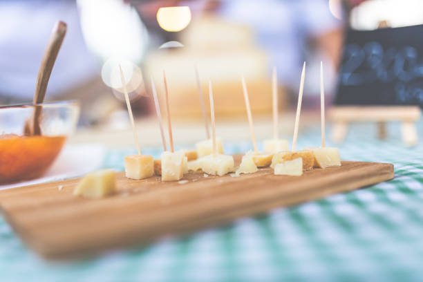 Close up of small cheese sample pieces with toothpicks on wooden cutting board. stock photo