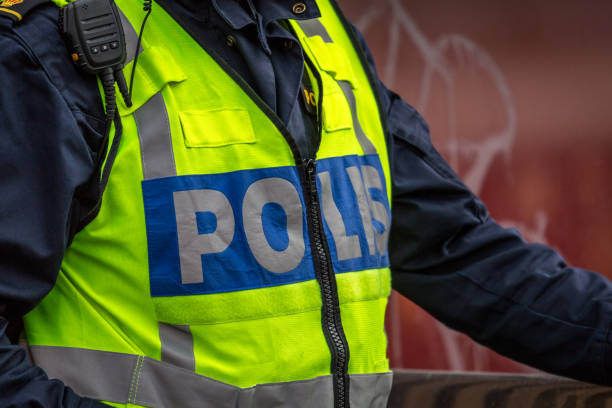 Close up of Swedish police officer wearing a luminous yellow green vest with police text. stock photo