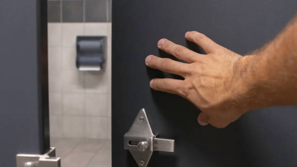 Close up of tan hairy man hand pushing open a bathroom stall stock photo