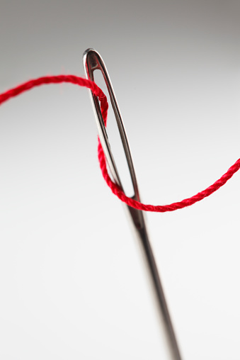Close Up Of Threading Eye Of A Needle With Red Thread Stock Photo ...