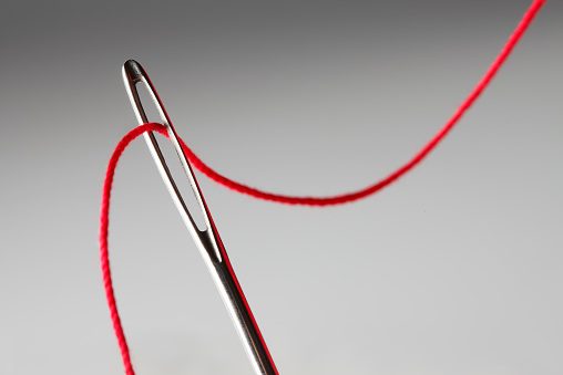 Close Up Of Threading Eye Of A Needle With Red Thread Stock Photo ...