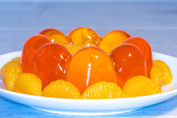 Close Up of Translucent Mouthwatering Orange Jelly Mould Close Up of translucent mouthwatering Orange Jelly/Jello Mould with orange segments, using a macro lens. gelatin dessert stock pictures, royalty-free photos & images