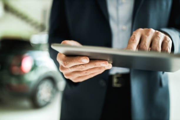디지털 태블릿을 사용하여 인식 할 수없는 자동차 판매인의 클로즈업. - car dealership 뉴스 사진 이미지