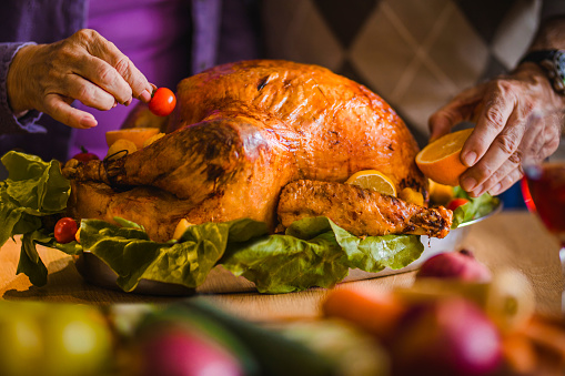 Close Up Of Unrecognizable Couple Decorating Thanksgiving Turkey