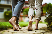 Close up of unrecognizable mature couple walking barefoot in the backyard.
