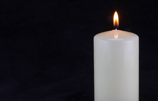 White candle isolated against a black background, with empty free space for text.