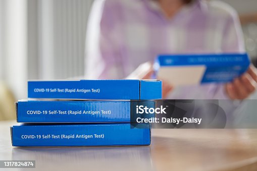 istock Close Up Of Woman At Home Reading Instructions On Supply Of Covid-19 Rapid Antigen Self-Testing Kits 1317824874