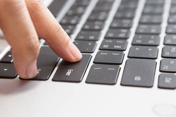 Close up of Woman hand pressing Enter button on laptop. stock photo