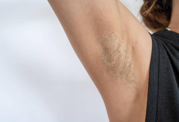 Close up of woman showing her unshaved armpit. Unshaven women often meet other criteria for traditional feminine beauty. macro body hair stock pictures, royalty-free photos & images