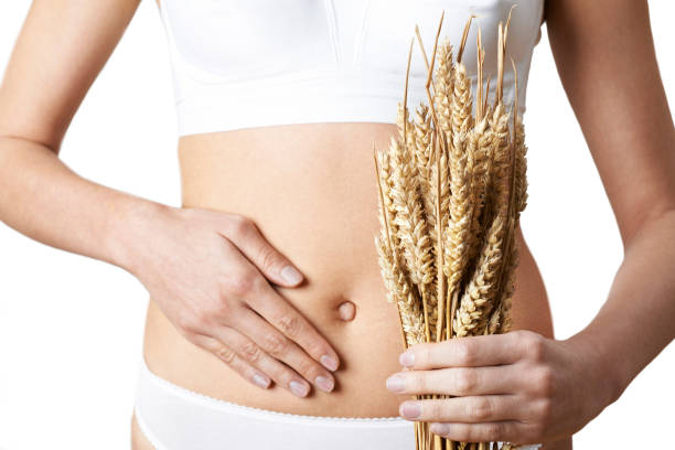 Close Up Of Woman Wearing Underwear Holding Bundle Of Wheat And Touching Stomach stock photo
