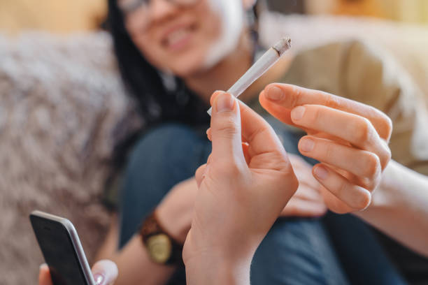Close up of young caucasian women smoking weed at home. Focus on joint People, Fun, Positive Emotion, Young Adult, Lifestyles little girl smoking cigarette stock pictures, royalty-free photos & images