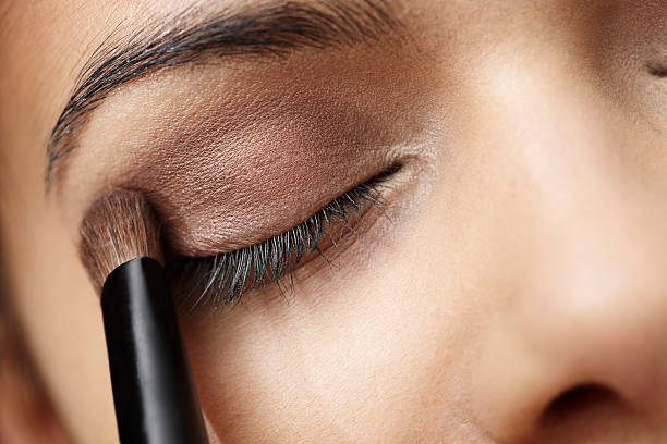 Close up of young woman applying eye shadow stock photo