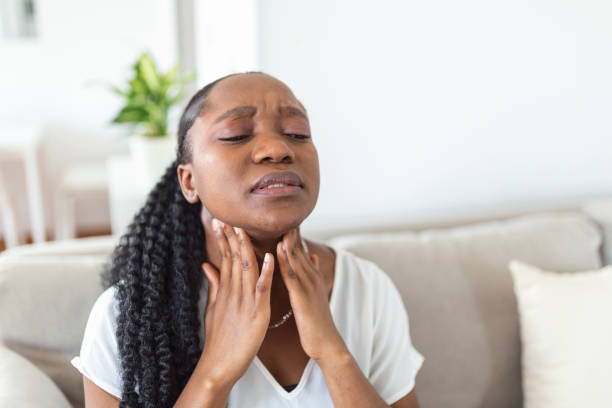 Close up of young woman rubbing her inflamed tonsils, tonsilitis problem, cropped. Woman with thyroid gland problem, touching her neck, girl has a sore throat stock photo