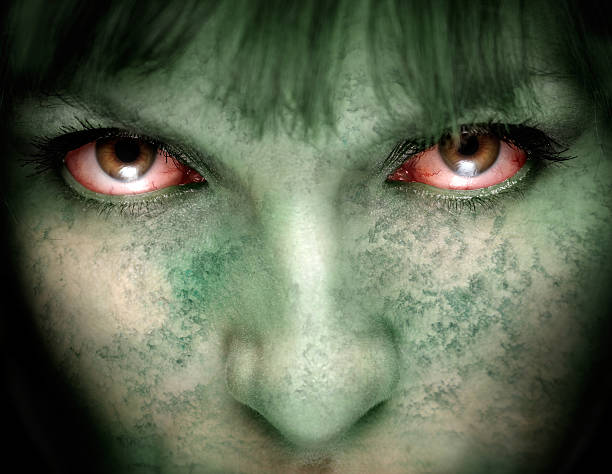Close up of zombie woman with green cloudy skin and red eyes stock photo