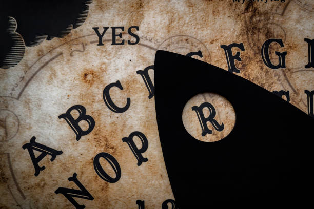 Close up on a ouija board Spirit-world game and witchcraft concept with a black magic board used on seances to invoke the spirits of the dead and talking to ghosts ouija board stock pictures, royalty-free photos & images