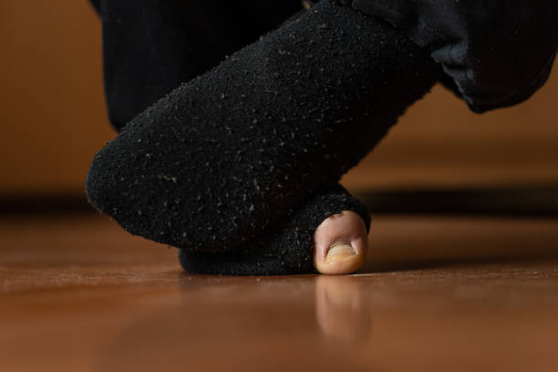 Close up on feet of unknown man wearing ripped socks with foot thumb protruding Close up on feet of unknown man wearing ripped socks with foot thumb protruding man pedicure stock pictures, royalty-free photos & images