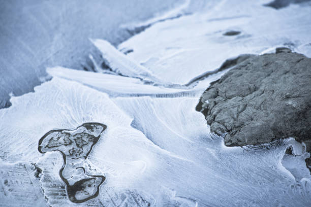 close up on lake bank rocks surrounded with cold frozen ice plaques on groundfloor stock photo
