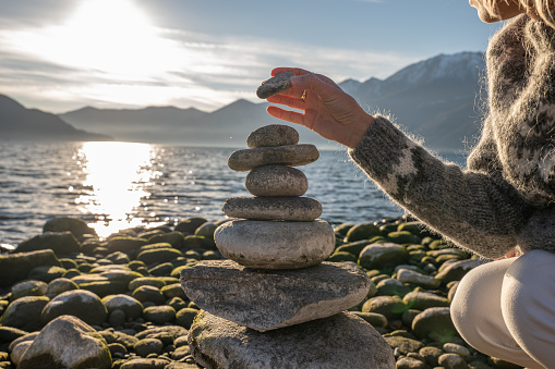 Close up on woman's hand stacking rock by the lake