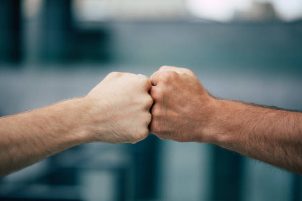 Close up outdoor photo of two men's fists holding together Close up outdoor photo of two men's fists holding together close to stock pictures, royalty-free photos & images