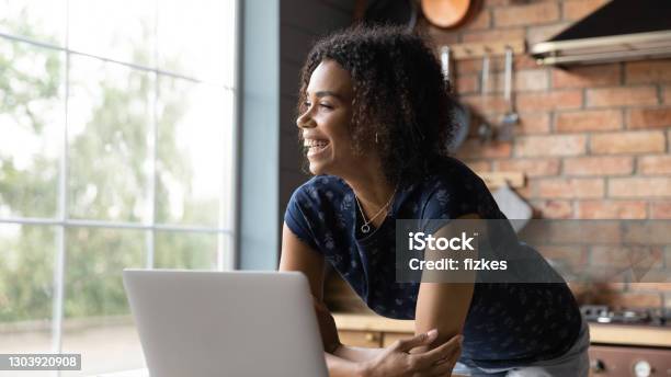 Close up overjoyed dreamy African American woman using laptop
