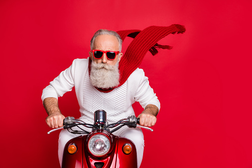 Close up photo of cool pensioner riding his bike with air wind blowing wearing white jumper sweater isolated over red background
