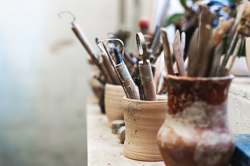 Close up photo of tools for ceramics work stand on window sill indoor workspace ready correct dishes or tableware form with copy space for text