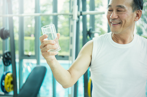 Close up portrait of asian senior man, thirsty asian senior man drinking a glass of water, refresh after workout
