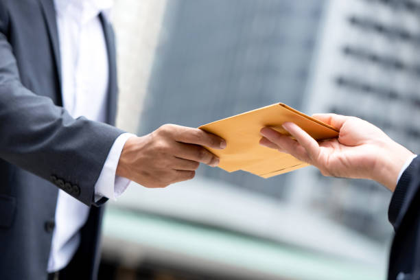Close up portrait of  businessman hand recieving yellow envelope Close up portrait of  businessman hand recieving yellow envelope from boss in urban city background bribing stock pictures, royalty-free photos & images