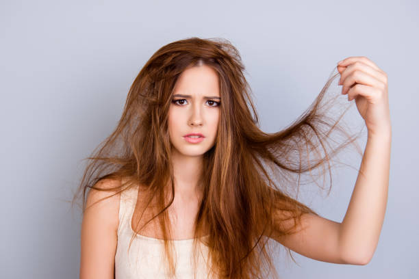 Close up portrait of frustrated young girl with messed hair on pure  background, wearing white casual singlet, holding her hair Close up portrait of frustrated young girl with messed hair on pure  background, wearing white casual singlet, holding her hair human hair stock pictures, royalty-free photos & images
