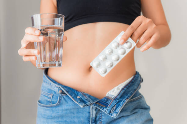 Close up portrait of woman showing diet pills and a glass of water, Healthcare and diet concept stock photo