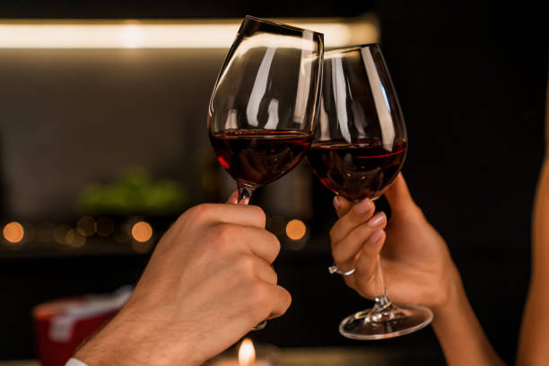 close-up shot van man en vrouw toasten en drinken van rode wijn uit glazen op het diner - wijn stockfoto's en -beelden