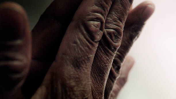 close up shot of the wrinkled hands of an old African American man, praying stock photo