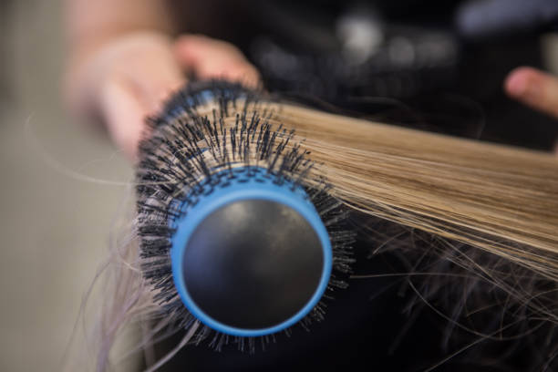 chiudi i capelli raddrizzare con spazzola per capelli e asciugacapelli in un parrucchiere - kostic foto e immagini stock