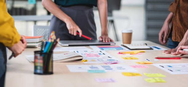 close up ux developer and ui designer brainstorming about mobile app interface wireframe design on table with customer brief and color code at modern office.creative digital development agency.panning - plano documento imagens e fotografias de stock