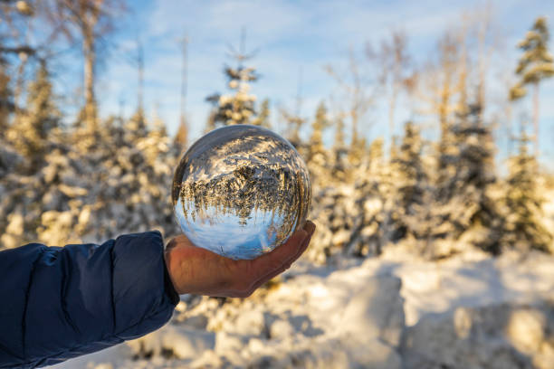 Close up view of hand holding crystal ball with inverted  image of winter natural landscape. Sweden. Close up view of hand holding crystal ball with inverted  image of winter natural landscape. Sweden. reentry stock pictures, royalty-free photos & images