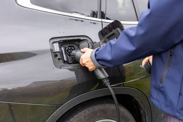 Close up view of man connecting charging cable to charging station for electric car. Sweden. stock photo