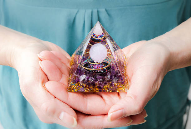 Close up view of woman hands holding and using Orgonite or Orgone pyramid at home while meditating. Converting negative energy to positive energy and have healing powers. stock photo