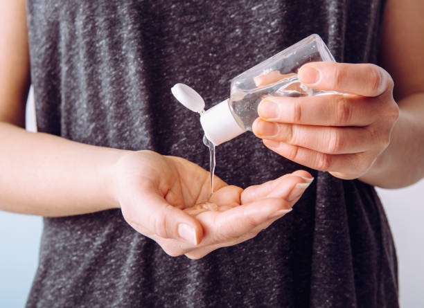 Close up view of woman person using small portable antibacterial hand sanitizer on hands.  disinfection stock pictures, royalty-free photos & images