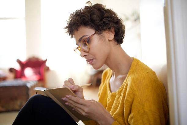 Close up young african american woman with glasses writing in book stock photo