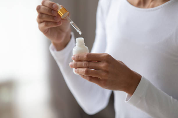Close up young woman holding bottle with pipette. Close up young woman holding bottle with pipette, using coconut moisturizing oil or pleasant fragrance liquid. Lady opening container with medical cosmetic product, beauty procedure at home. acid stock pictures, royalty-free photos & images