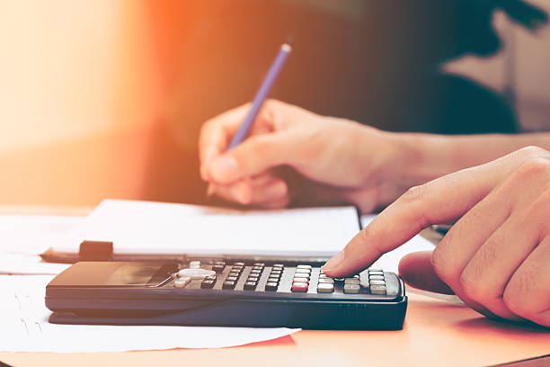 Close up young woman with calculator counting making notes Close up young woman with calculator counting making notes at home, hand is writes in a notebook. Savings, finances, concept. Calculator stock pictures, royalty-free photos & images