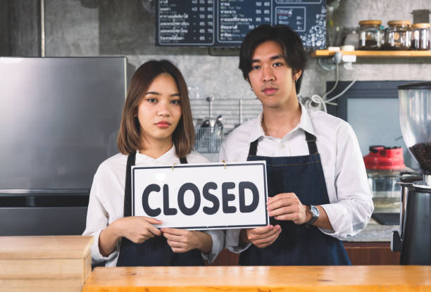 Closed coffee shop A young couple man and female overturned a label to close they business because of loss in selling coffee stock photo