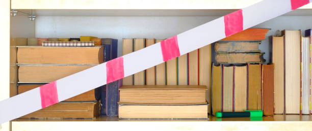 closed library due to corona lockdown,row of books, bookshelf with barrier tape, concept stock photo