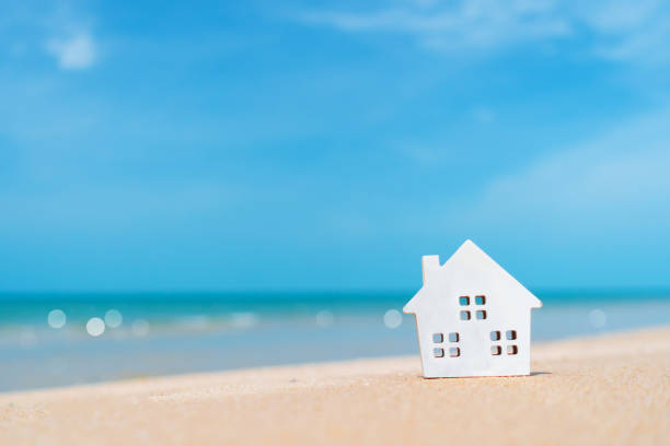 cerrado pequeños modelos domésticos en la arena con la luz del sol y el fondo de la playa. - tangram casa fotografías e imágenes de stock
