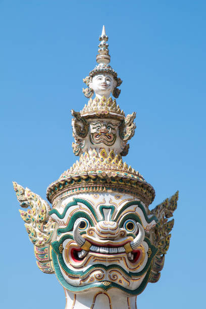 Closeup Ancient Head and face of Thai big giant statue with blue sky, Royal Grand Palace (Wat pha kaew) with blue sky, Bangkok in Thailand. stock photo