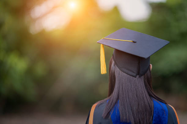 closeup behind a female college graduate wearing a black fringe gown and a black hat, Concept of Successful Education in Hight School,Congratulated Degree stock photo