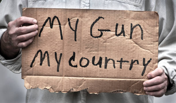 Closeup cardboard homemade sign My Gun My Country Man holding My Gun, My Country, handwritten cardboard sign, gun laws, second amendment rights, NRA, mass shootings, freedom, liberties, nra stock pictures, royalty-free photos & images